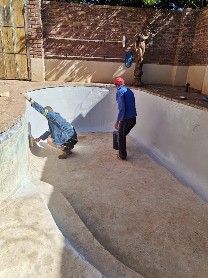 workers applying supa rubber to inside of swimming pool